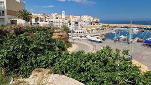 A coastal town with buildings, a marina, and a clear sky.