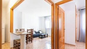A spacious room with a dining area, a sofa, and a large wooden door.