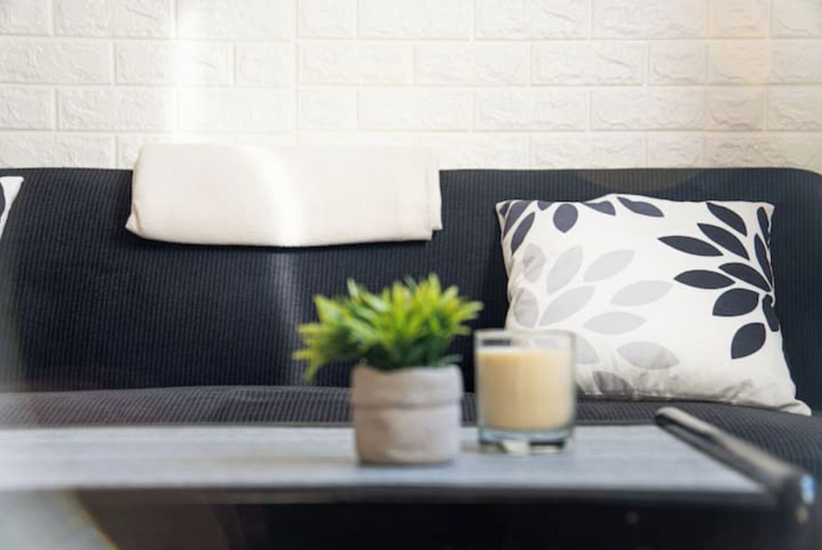 A modern living room with a black and white sofa, a small plant, and a glass of milk on a table.