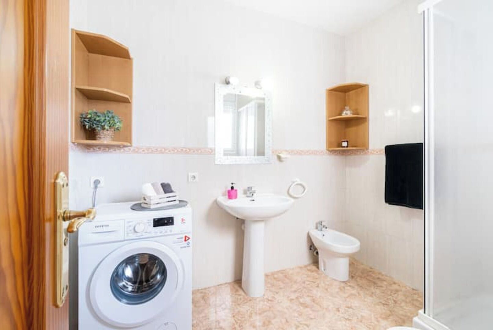 A compact bathroom with a washing machine, sink, and bidet.