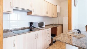 A compact kitchen with light wood cabinets, a microwave, a sink, and a small countertop.