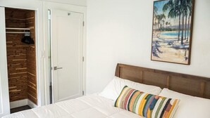 Ein Schlafzimmer mit einem Bett, einem Holzschrank und einem Strandbild an der Wand.