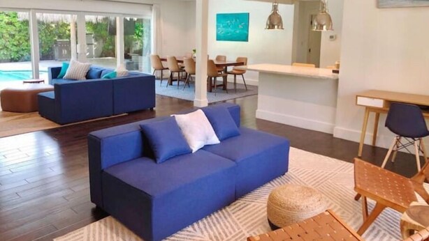 Ein modernes Wohnzimmer mit einem blauen Sofa, einem Essbereich und einer Küche.