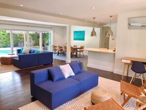 A modern living room with a blue sofa, a dining area, and a kitchen. - Villa Palma: Hollywood Beach Walk-Private Pool & Tiki Hut-October November Deal (Hollywood)