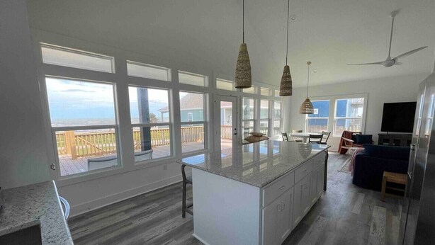A spacious kitchen with a large island, a dining area, and a balcony with a view. - Breezy Ocean View/Sleeps 10/Steps To Beach/Central (Bolivar Peninsula)