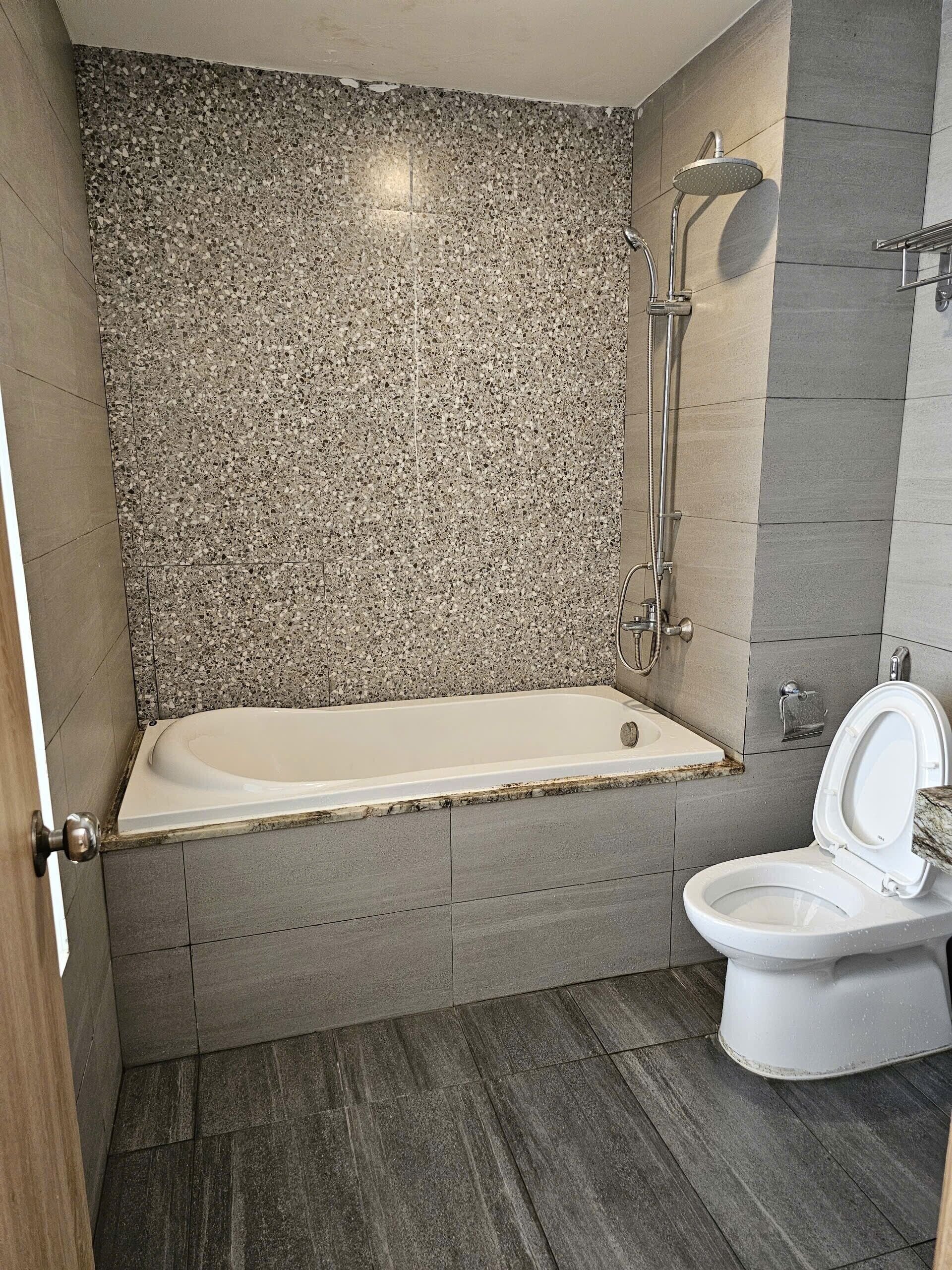 Een badkamer met een bad, toilet en douche.