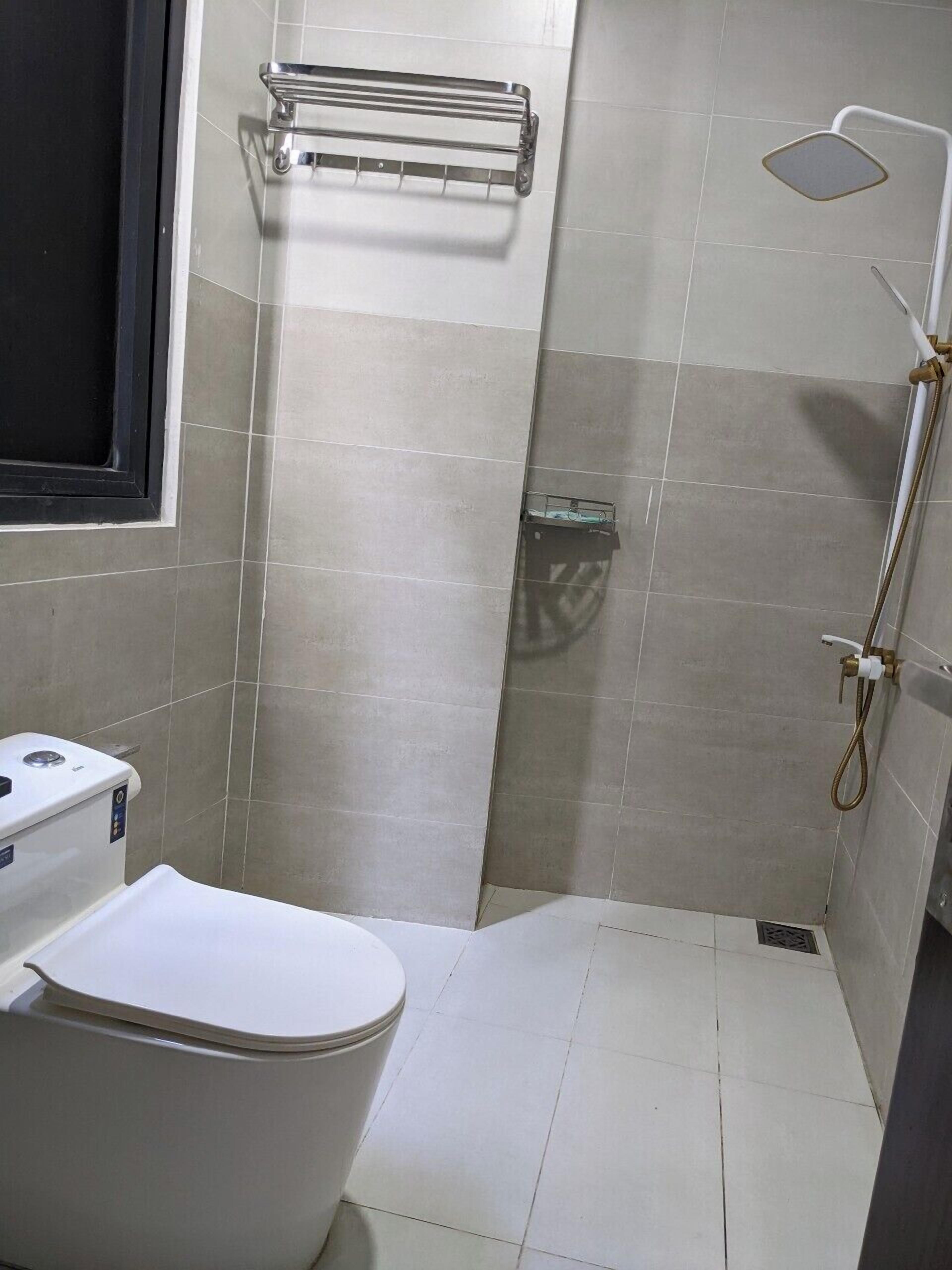 Un baño pequeño con inodoro, ducha y toallero.