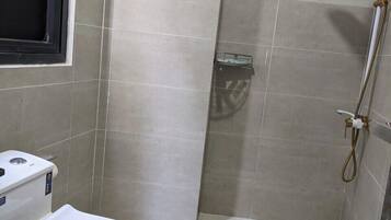 Un baño pequeño con inodoro, ducha y toallero.