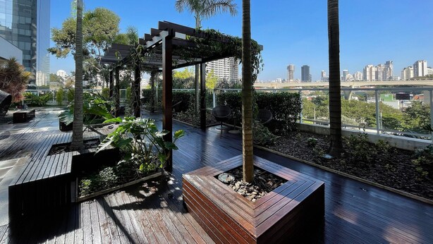 Un jardin sur le toit, doté d’une terrasse en bois, de jardinières et d’une pergola.
