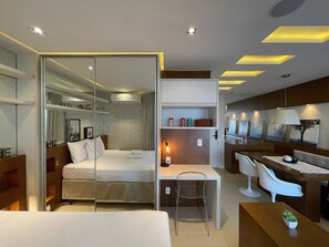 A modern hotel room with a bed, a desk, and a seating area.
