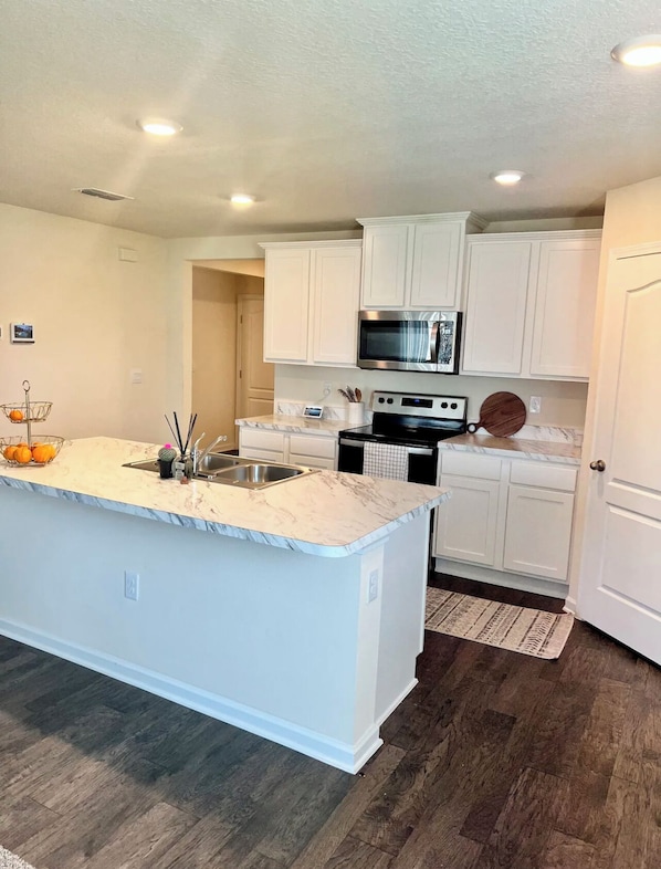 A modern kitchen with white cabinetry, a stainless steel microwave, and a black stove.
