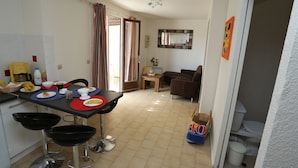 A compact living space with a dining area, a kitchen, and a small seating area.