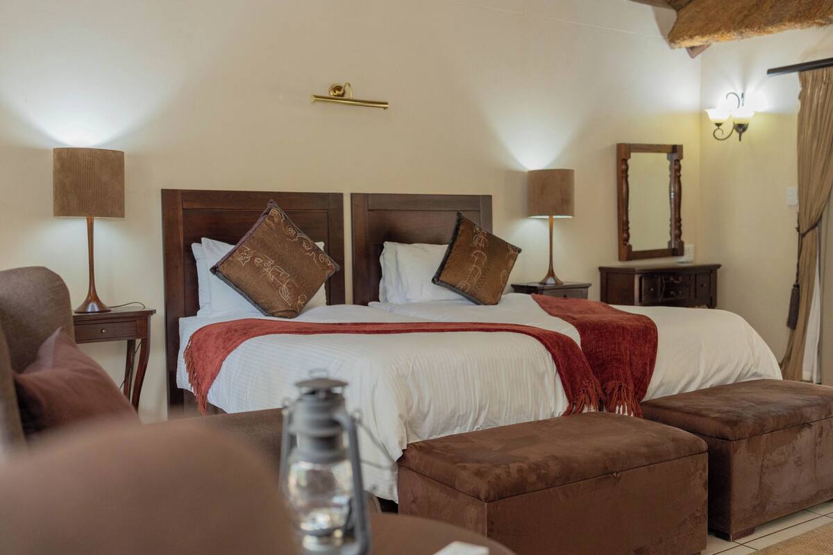 A bedroom with a large bed, two bedside tables, a nightstand, a mirror, and a lamp.