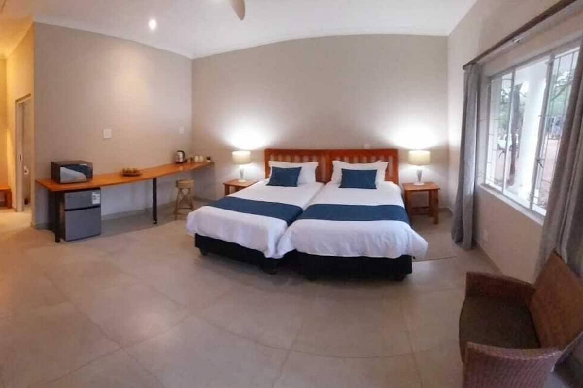 A hotel room with a double bed, a desk, a chair, and a window.