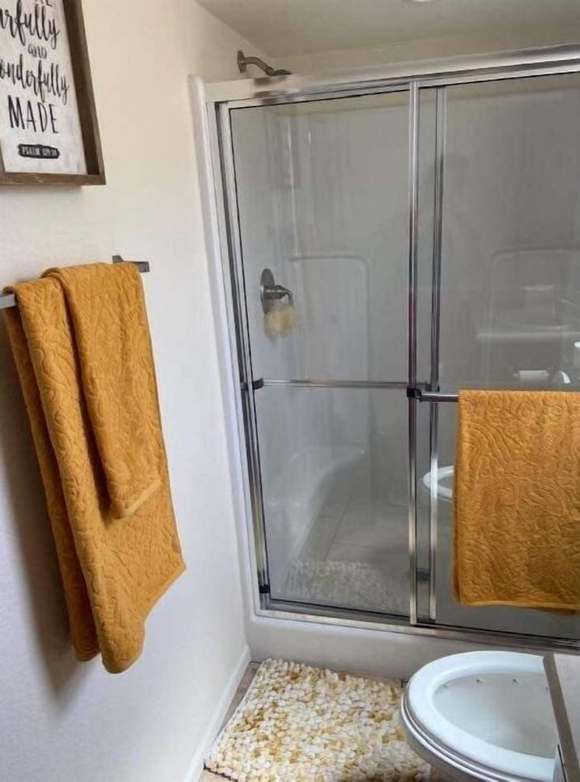 Une salle de bain avec une douche à parois de verre, des toilettes et un porte-serviettes sur lequel est posée une serviette marron.