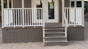 Ein kleines, eingeschossiges Gebäude mit einer Veranda, einer Tür und einer kleinen Treppe, die zum Eingang führt.