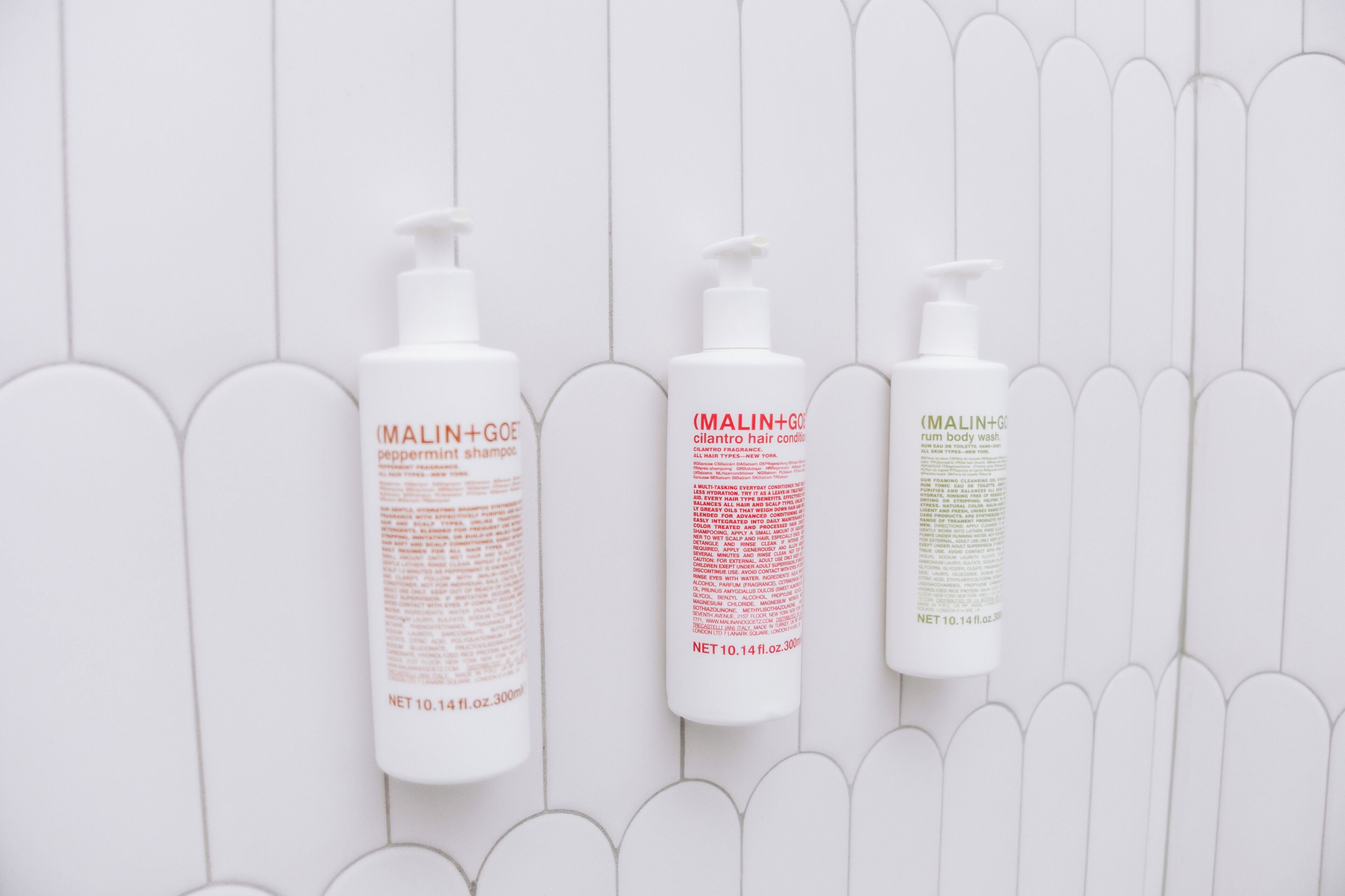 Drie flessen MALIN+GOE producten voor een witte achtergrond.