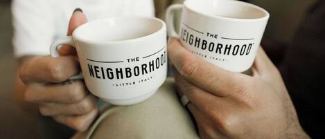 Two white mugs with the text "The Neighborhood" and "Little Italy" on them.