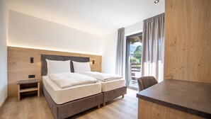 Ein modernes Hotelzimmer mit einem hölzernen Kopfteil, einem Bett mit weißer Bettwäsche, einem kleinen Nachttisch und einem Esstisch.