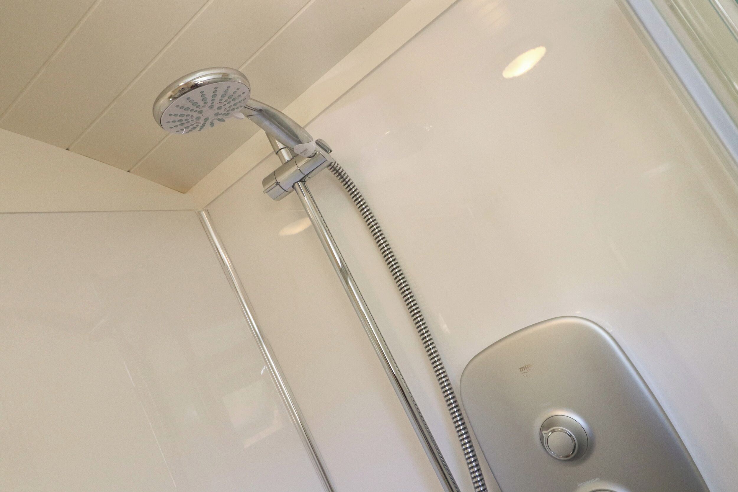 Une douche équipée d’un pommeau de douche à main et de commandes murales.