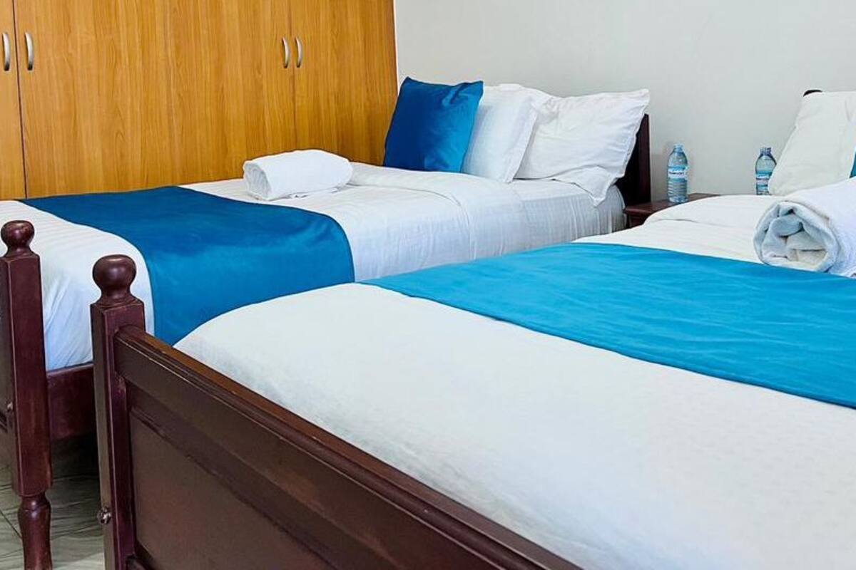 A hotel room with two single beds, wooden headboards, and a wardrobe.