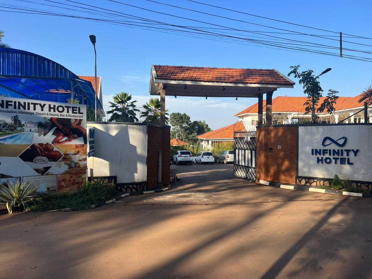 The Infinity Hotel entrance with a covered walkway, palm trees, and parked cars.