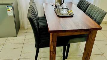 A dining area with a wooden table, black upholstered chairs, and a small refrigerator.