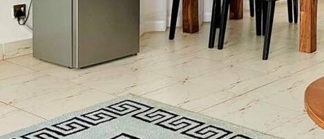 Une pièce comprenant une table à manger, des chaises, un téléviseur fixé au mur et un réfrigérateur.