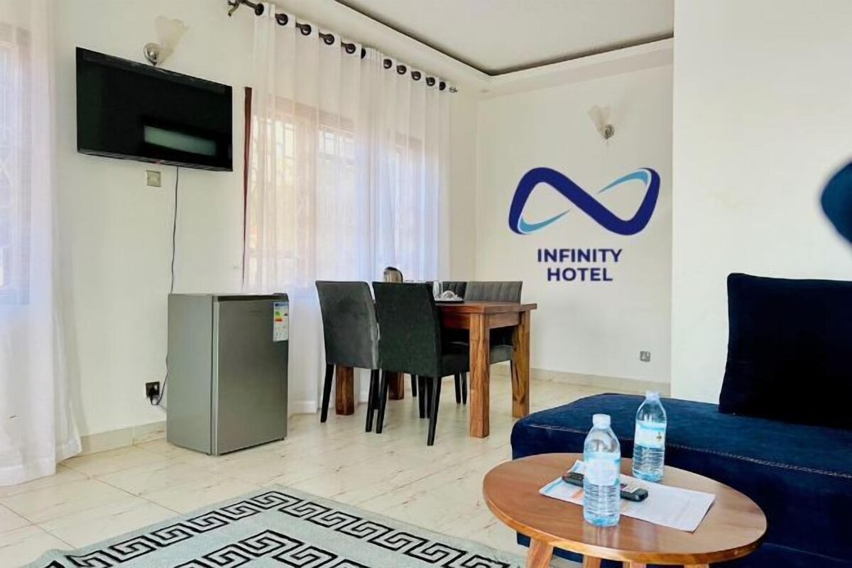 Habitación de hotel con comedor, televisión, refrigerador y sofá.
