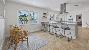 Una cucina moderna con isola centrale, sgabelli da bar e vista sull'oceano.
