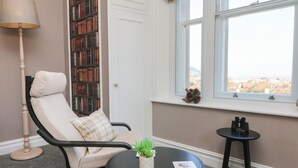 A cozy reading nook with a chair, a small table, a lamp, and a bookshelf. - The Outlook (Minehead)