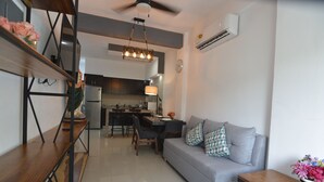 A modern living room with a grey sofa, wooden coffee table, and a dining area with a table and chairs. - Condo near Gourmet District + Pool 1BD Unit1
 (Puerto Vallarta)