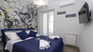 Een slaapkamer met een bed, kussens, een televisie en een radiator.