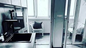 Een moderne keuken met een inbouwoven, een eethoek met een stoel, en een groot raam.