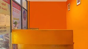 Un espace d’accueil avec un mur de couleur orange vif et un comptoir de réception.