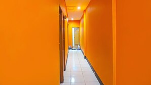Un long couloir étroit aux murs d’un orange vif et au sol recouvert de carreaux blancs.