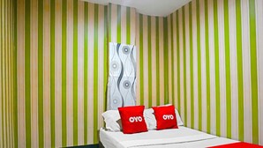 Une chambre d’hôtel avec un lit, un papier peint à rayures et une couvre-lit à motifs.