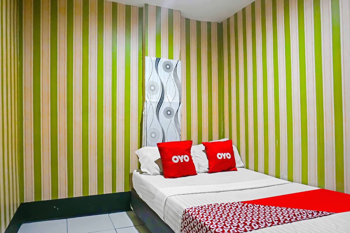 Een hotelkamer met een bed, streepverf en een bedovertrek met dessin.