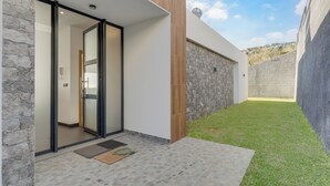 A modern building with a stone exterior, a glass door entrance, and a small grassy area in front. - Casa Mozart II (Estreito da Calheta)