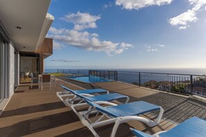 Relax on the ocean-view deck with lounge chairs and a pool, taking in the distant shoreline.