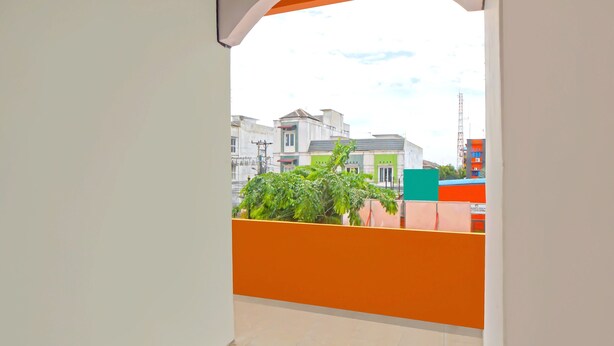 A balcony with a view of buildings and a plant.