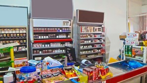 A pharmacy with shelves stocked with various health products, a counter with snacks and beverages, and a window with a view of the street.