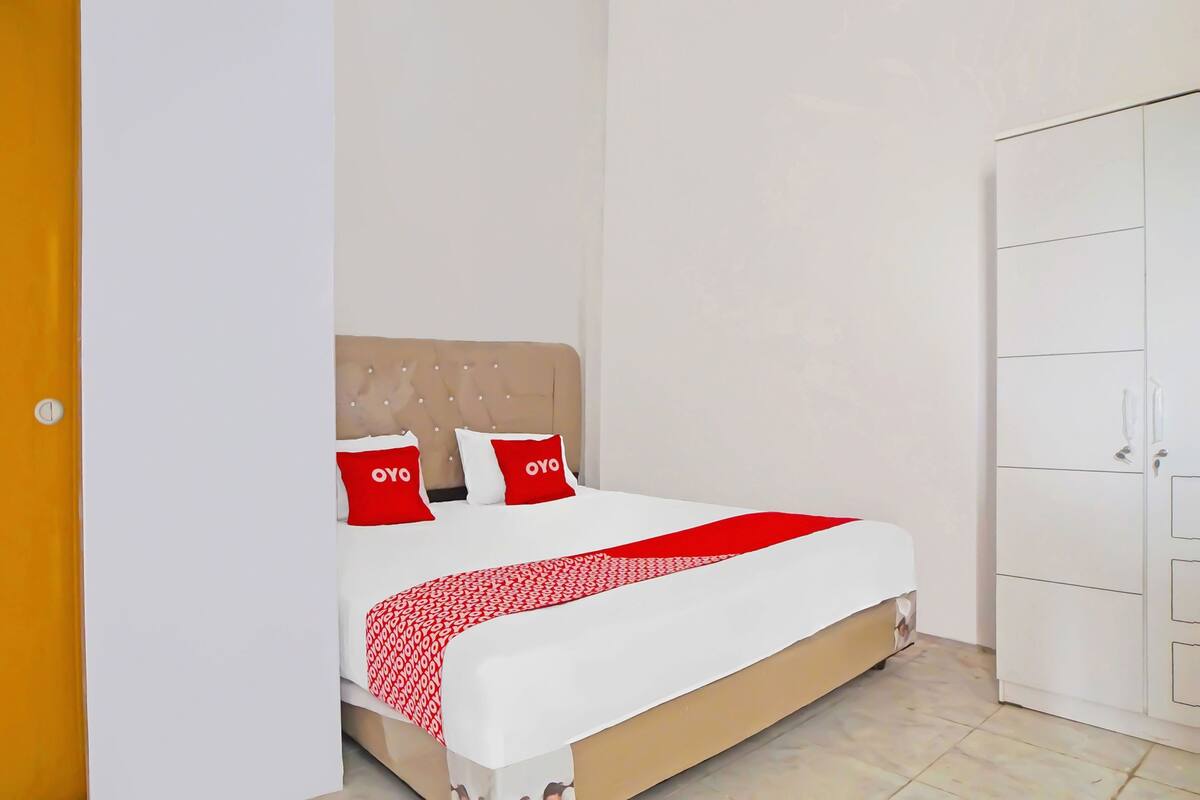 A bedroom with a bed, two pillows, a bedside table, and a wardrobe.