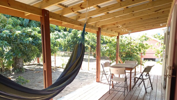 A wooden deck with a hammock, a table, and chairs. - Comfortable, local home with A/C and private verandah (Calibishie)