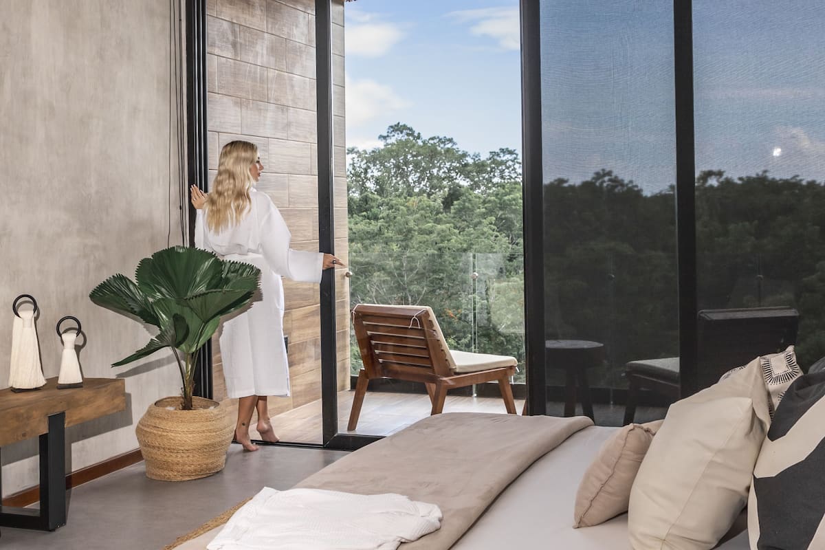A modern room with a large window, a wooden chair, a sofa, and a plant.