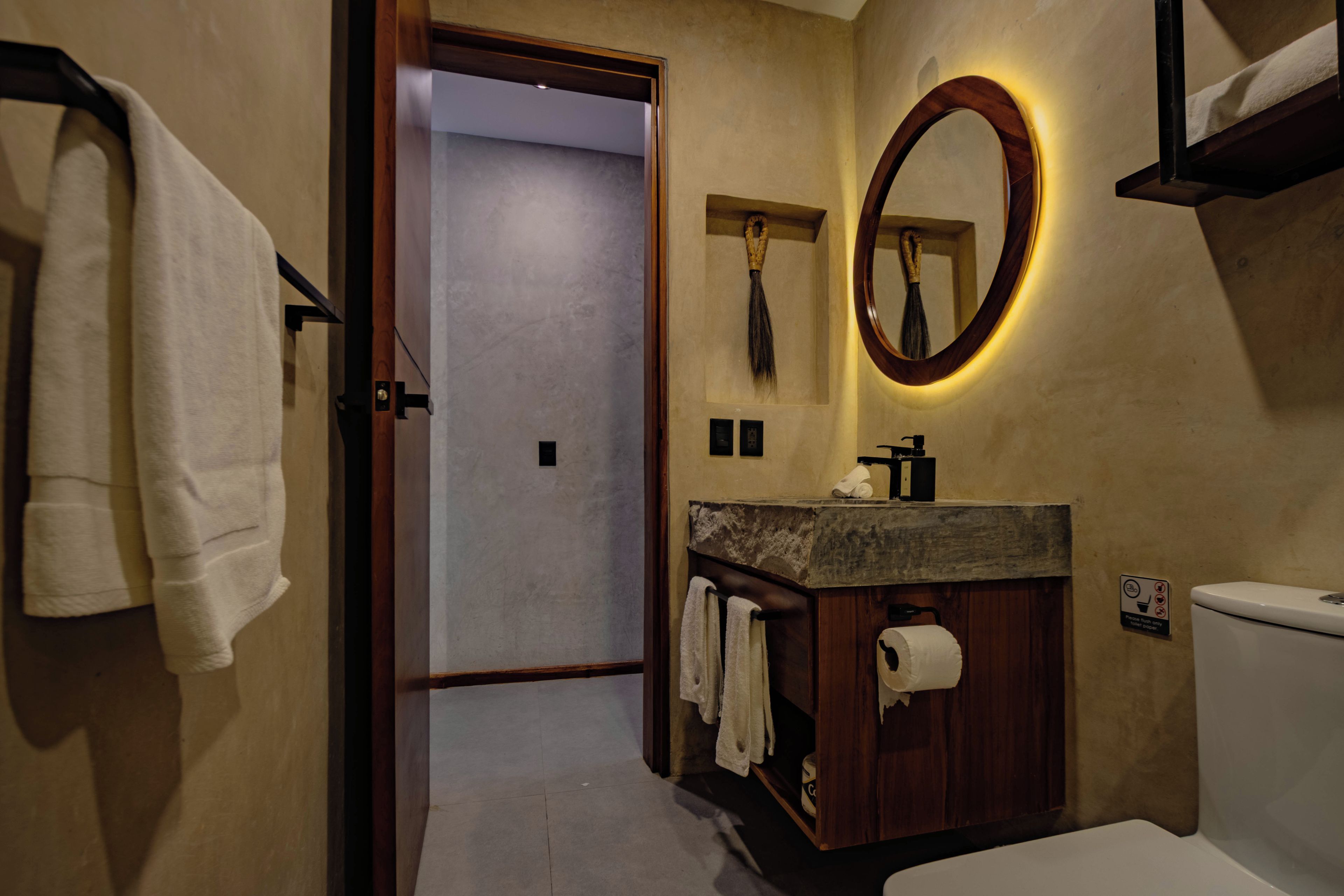 Une salle de bain avec un meuble-lavabo en bois, des toilettes, un miroir avec un cadre en bois et un porte-serviettes.