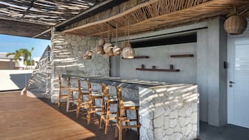 A bar area with stone walls, wooden chairs, and hanging light fixtures.