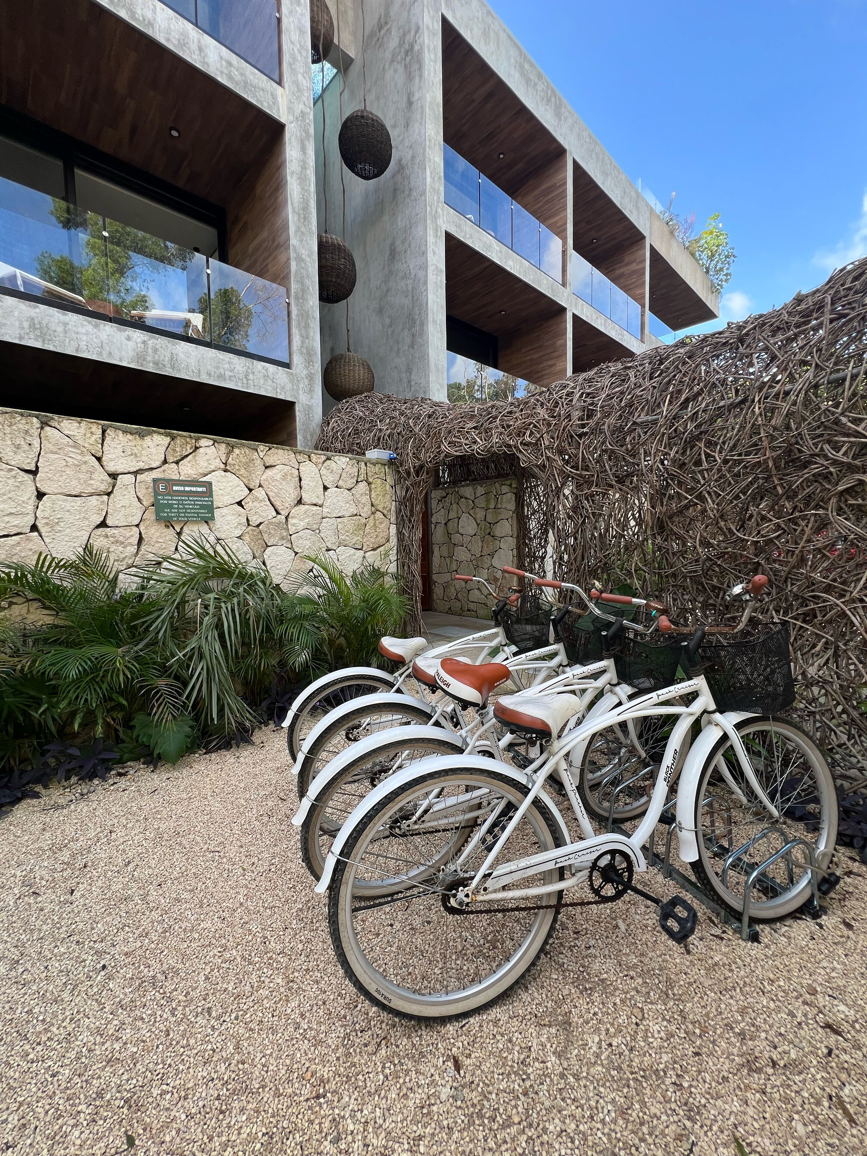 A modern building with a stone facade, a thatched roof structure, and a gravel driveway.
