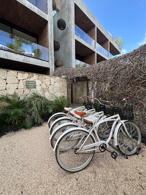 A modern building with a stone facade, a thatched roof structure, and a gravel driveway.