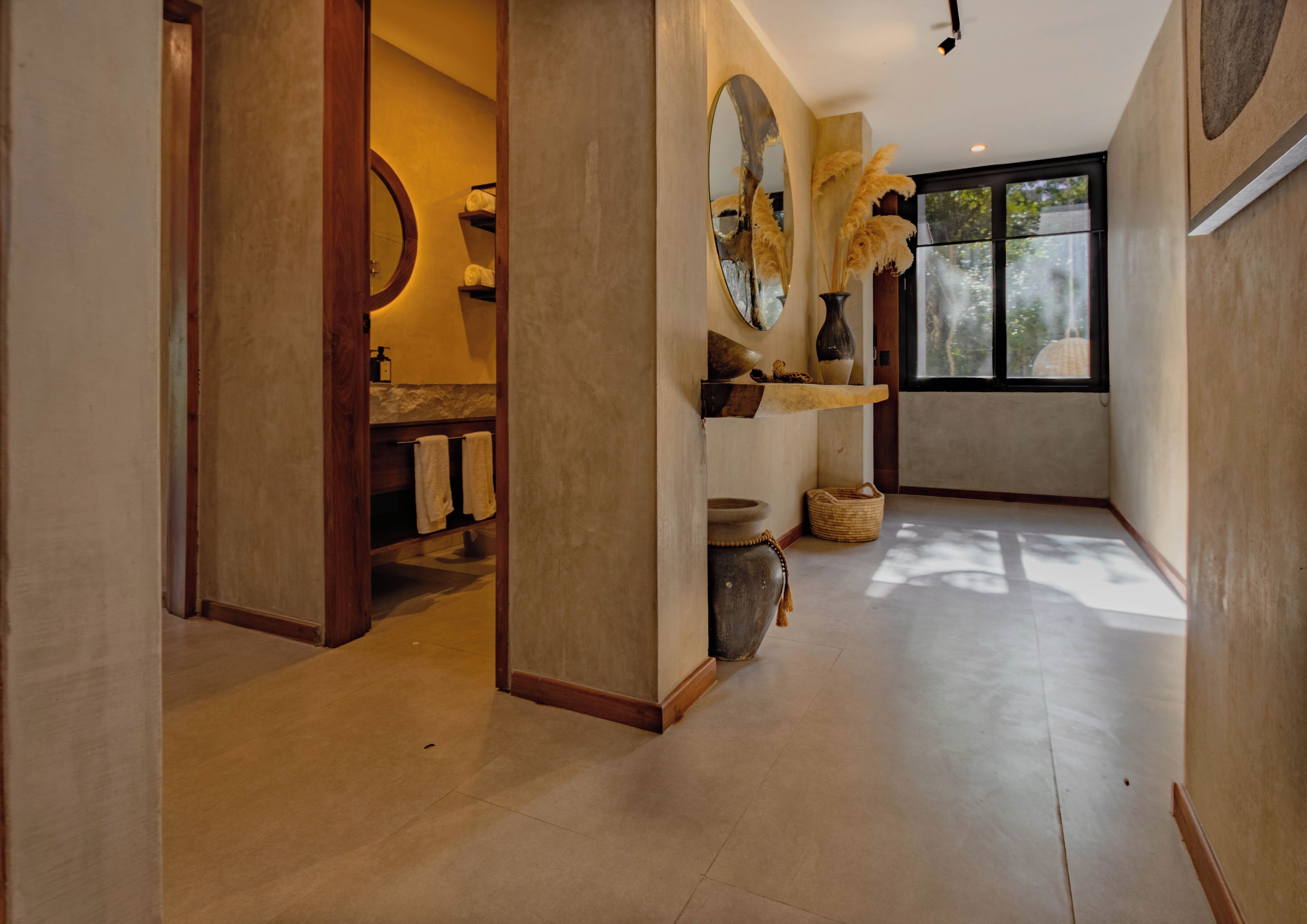 A modern bathroom with a large mirror, wooden shelves, and a window providing natural light.